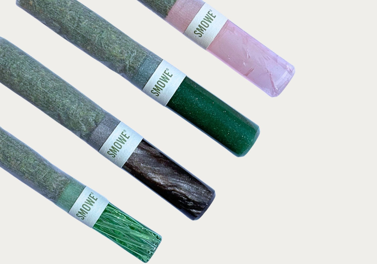 Vier SMOWE J-Bands Papierbanderolen an Kräuter-Zigaretten mit verschiedenen farbigen Glas-Tips.